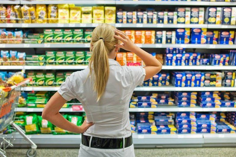 Uma mulher está olhando as prateleiras de um supermercado.