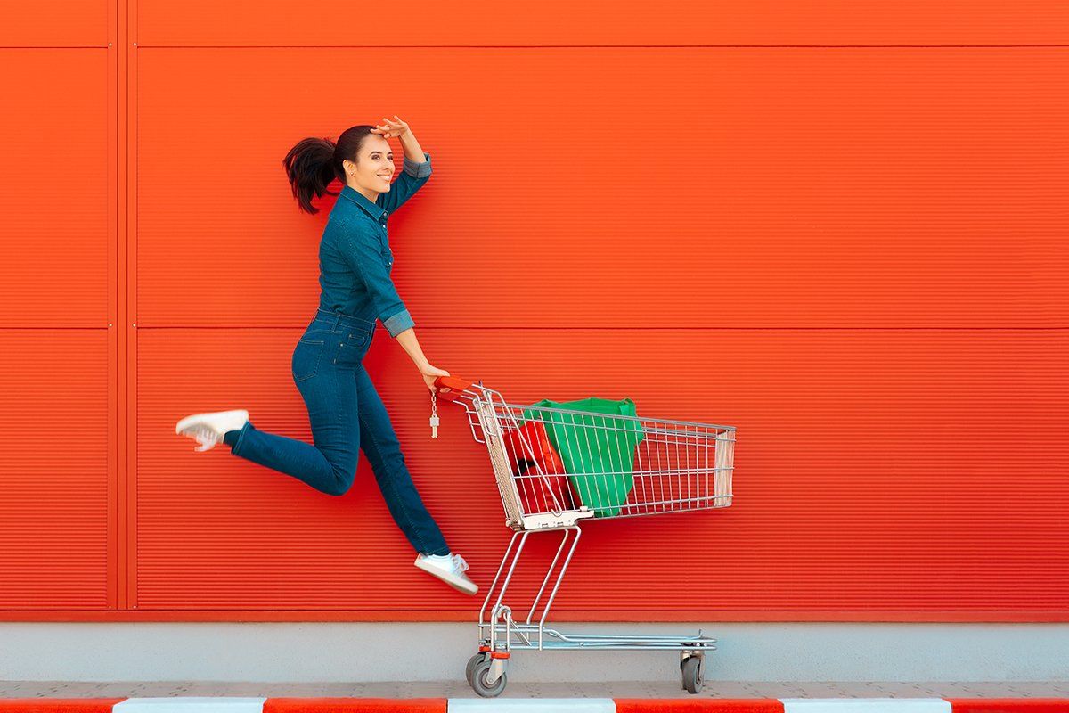 Uma mulher está pulando enquanto empurra um carrinho de compras.