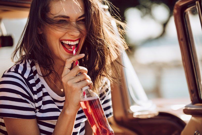 a woman is drinking a drink through a straw in the back of a car .