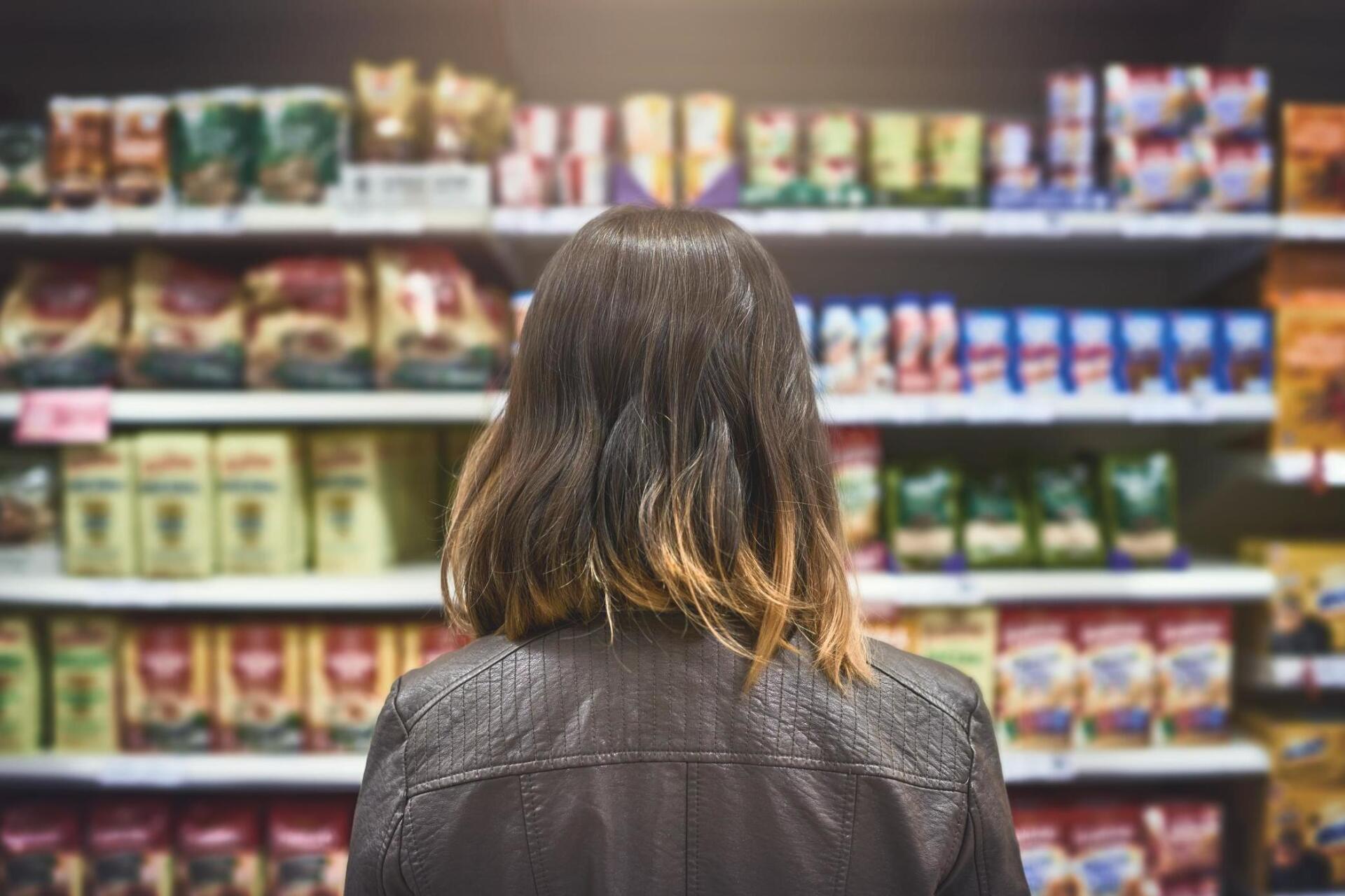 Uma mulher está olhando as prateleiras de um supermercado.