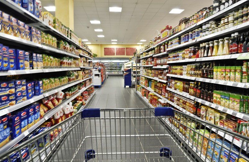 an empty shopping cart in an aisle of a grocery store .