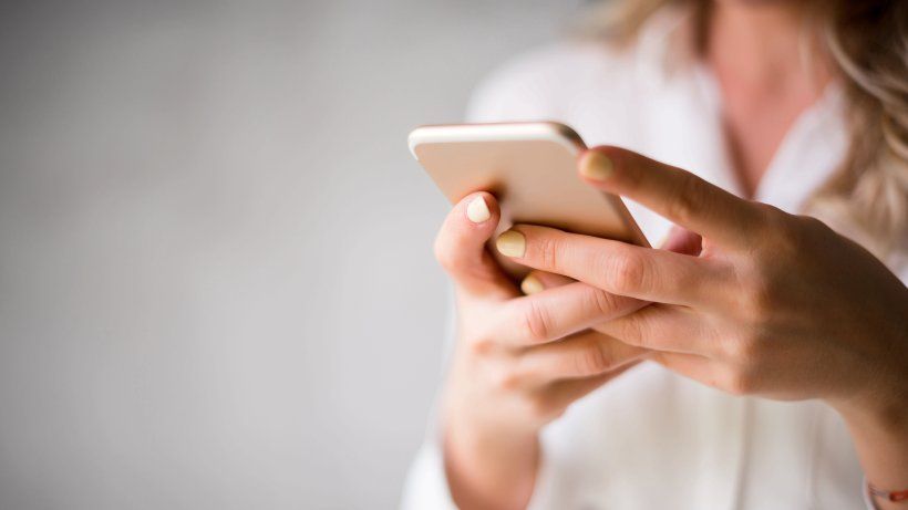 uma mulher está segurando um telefone celular nas mãos.