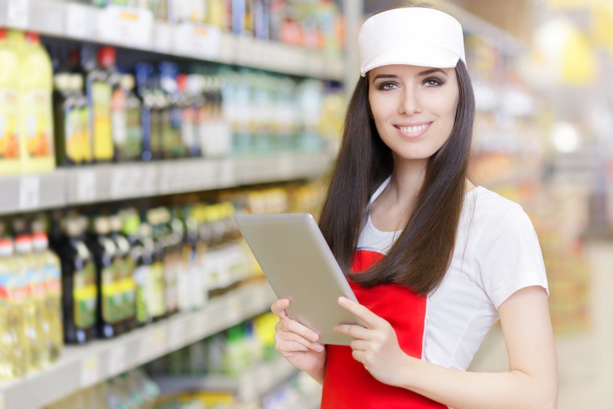 Uma mulher está segurando um tablet em um supermercado.