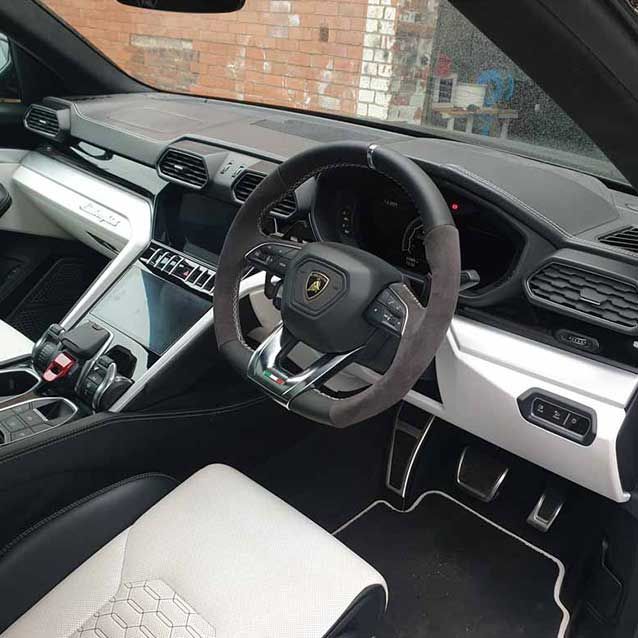 Luxury sports car interior with white seats, black dashboard, and right-hand steering wheel