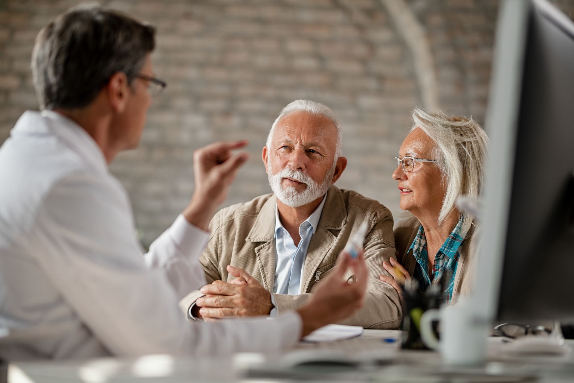 Senior couple meeting with a financial advisor at a desk with a computer
