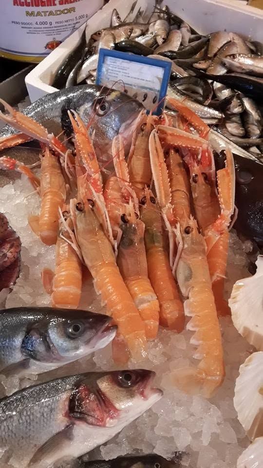 Assortimento di pesce fresco e gamberetti su ghiaccio in un mercato del pesce.