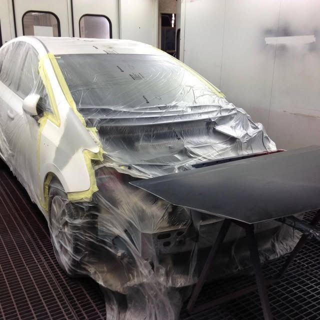Auto verniciata in cabina di verniciatura, mascherata con pellicola di plastica e pronta per la carrozzeria.