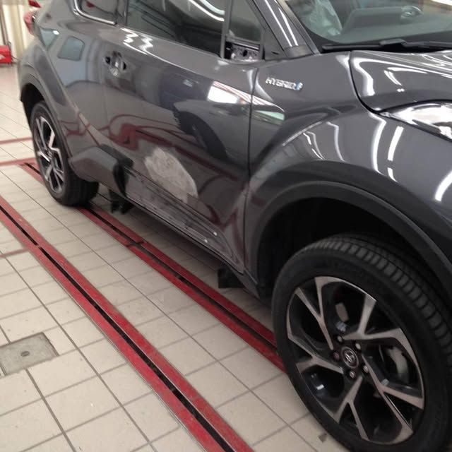 SUV grigio in uno showroom, vista laterale su pavimento piastrellato con segnaletica orizzontale rossa.