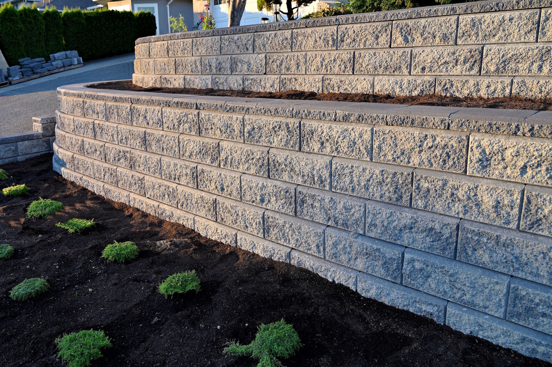 Stone retaining walls with tiered landscaping in an outdoor setting.