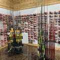 Fishing rod display wall in a tackle shop, with rows of packaged lures and rods on stands.