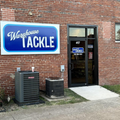 Warehouse Tackle storefront on a brick building with a blue sign and glass entrance door
