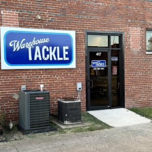 Warehouse Tackle storefront on a brick building with a blue sign and glass entrance door