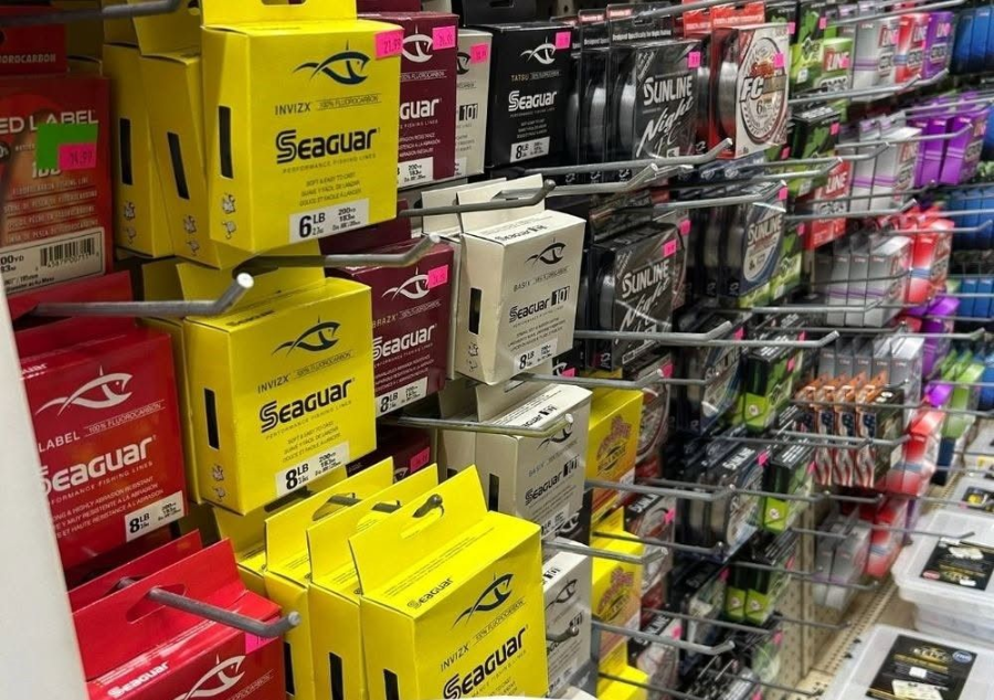 Shelves stocked with colorful Seaguar fishing line spools and tackle accessories in a store aisle