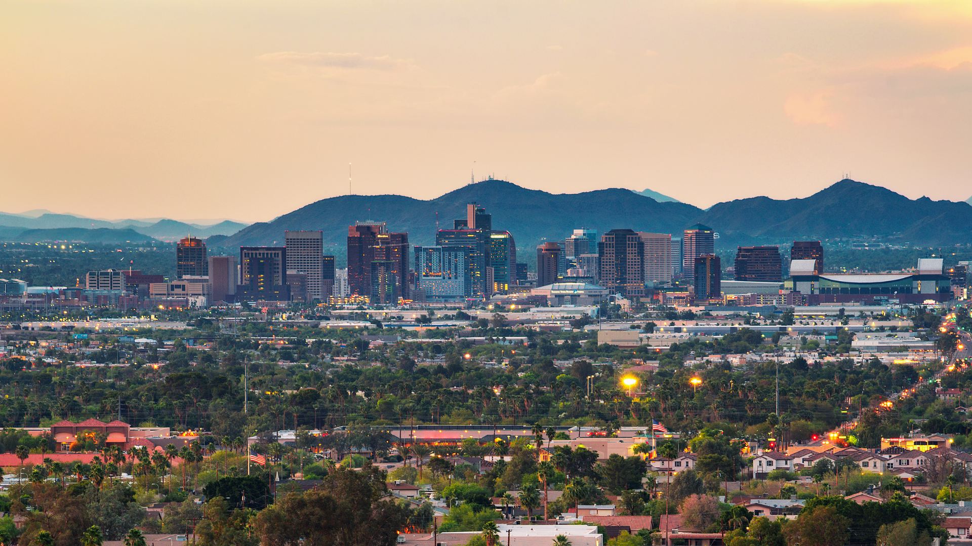 An aerial view of a city skyline with mountains in the background.