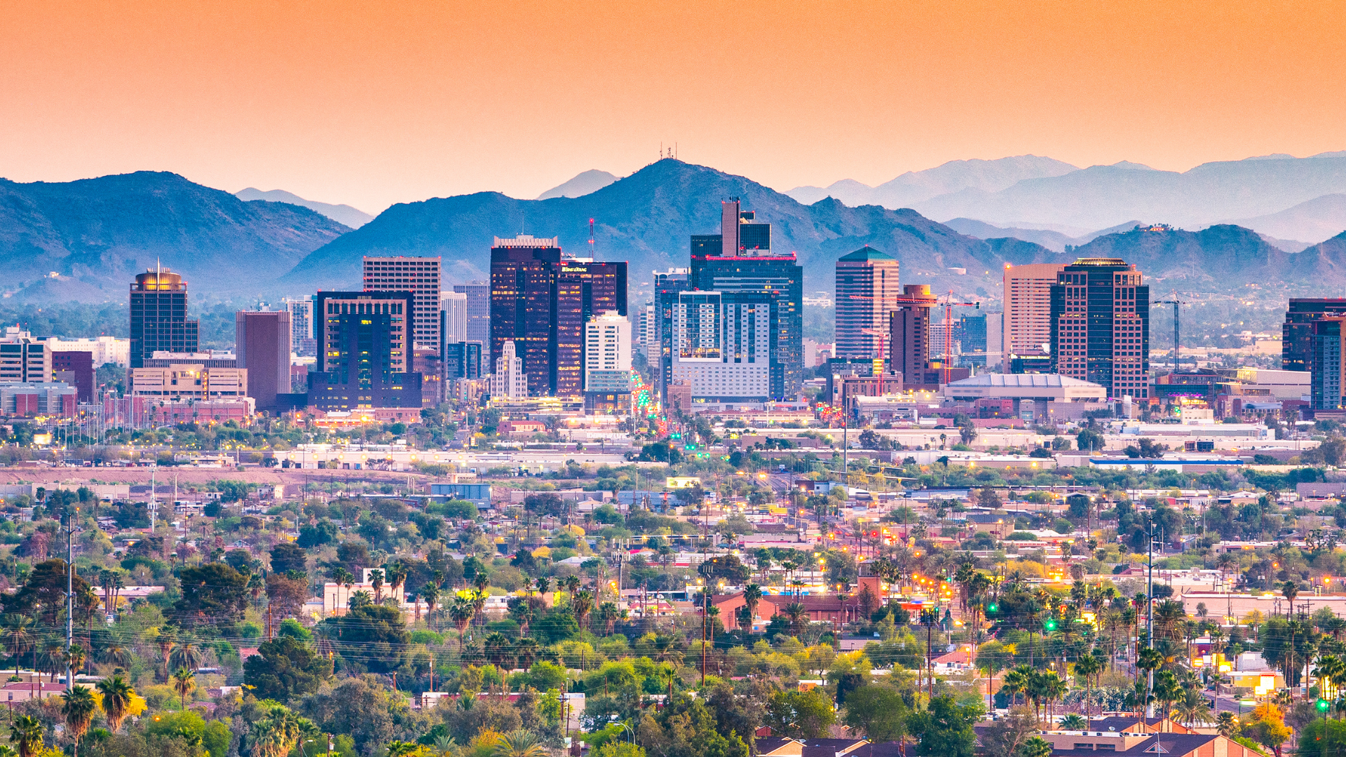 An aerial view of a city skyline with mountains in the background.