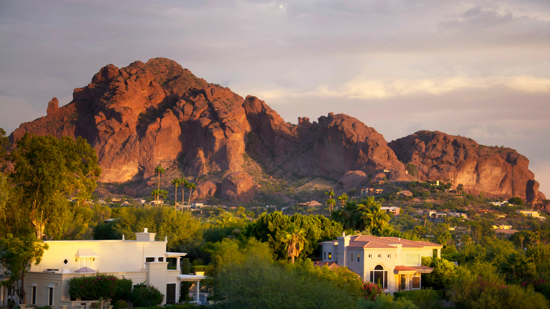 A mountain range with houses in the foreground and trees in the background