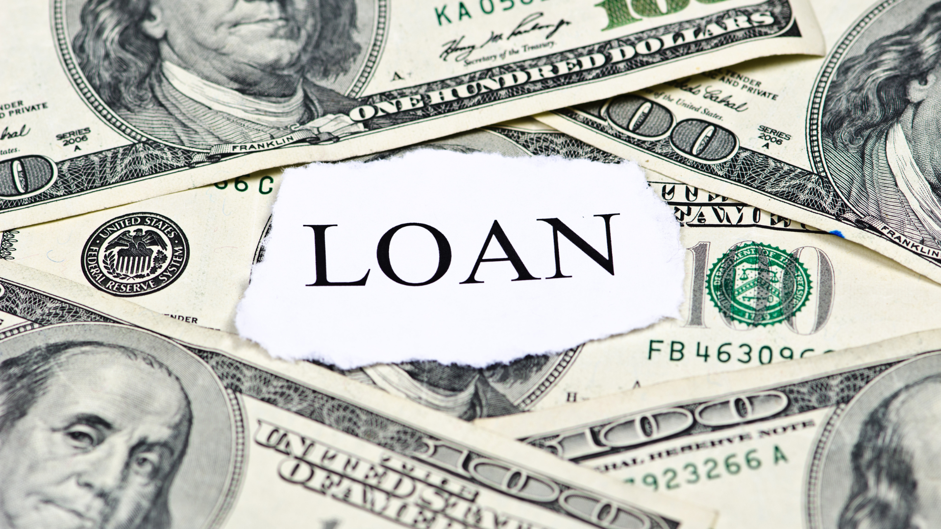 A pile of money with the word loan written on a piece of paper.