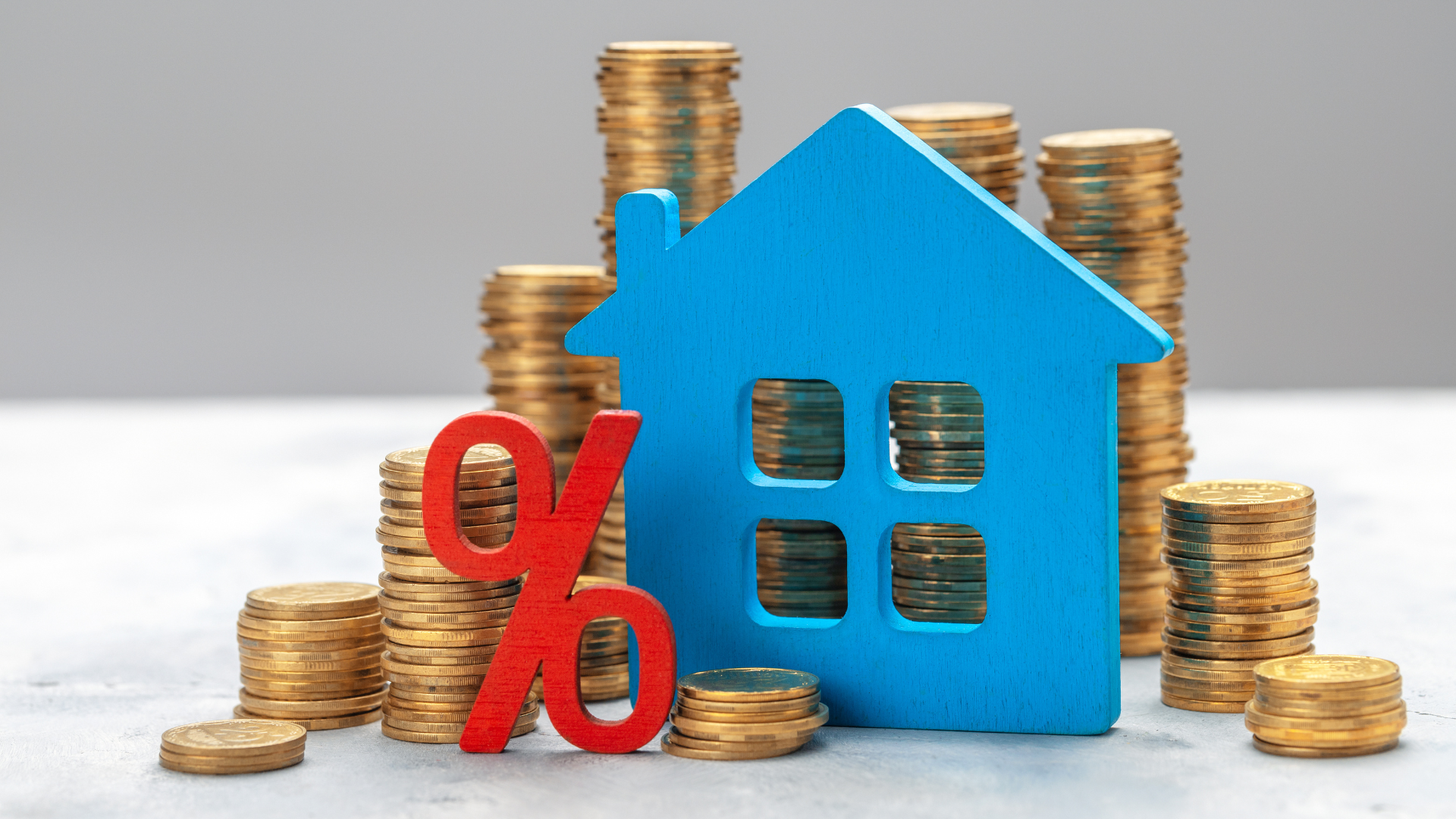 A blue house is sitting on top of a pile of coins.