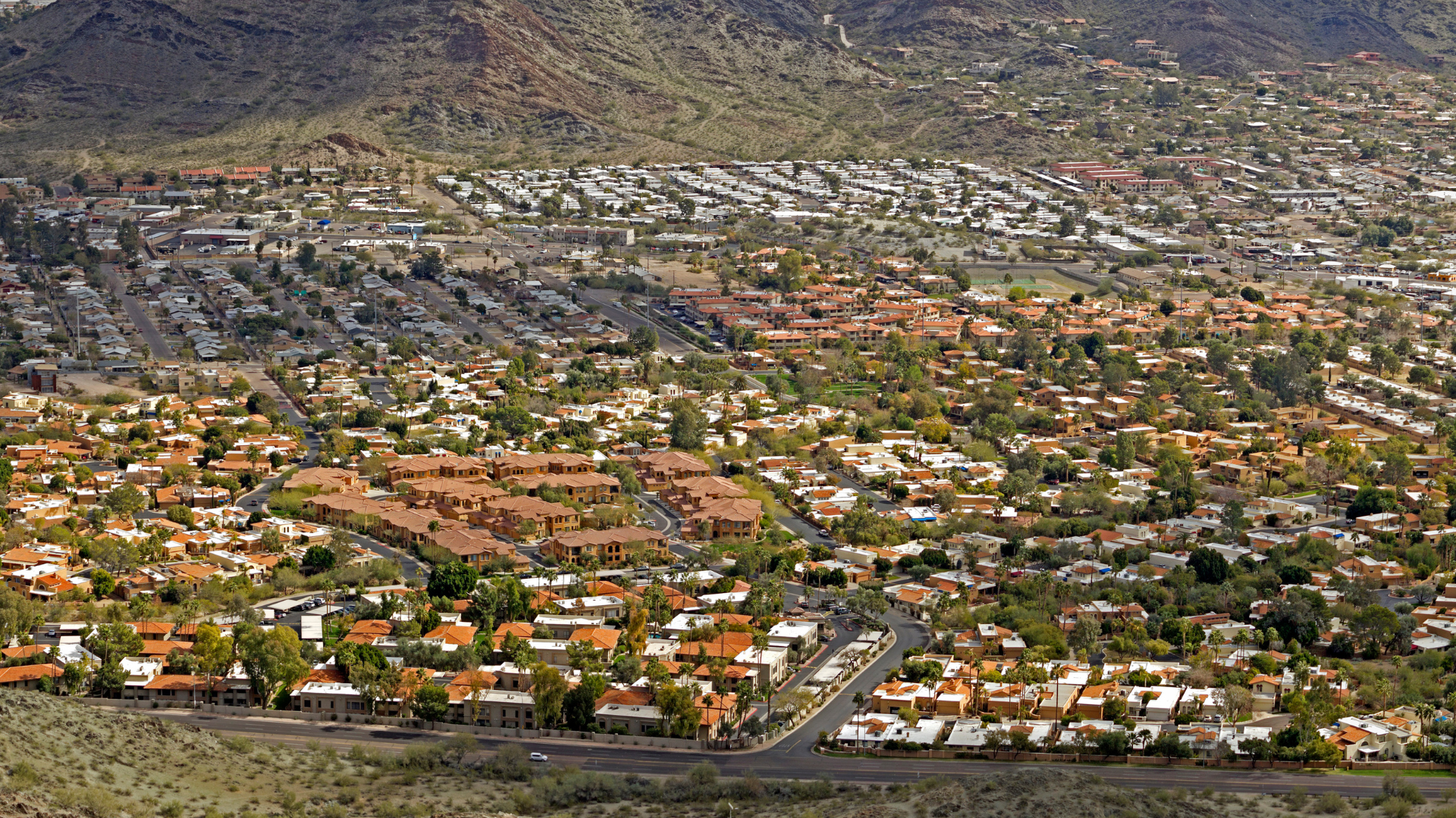 An aerial view of a residential area in the desert with mountains in the background.