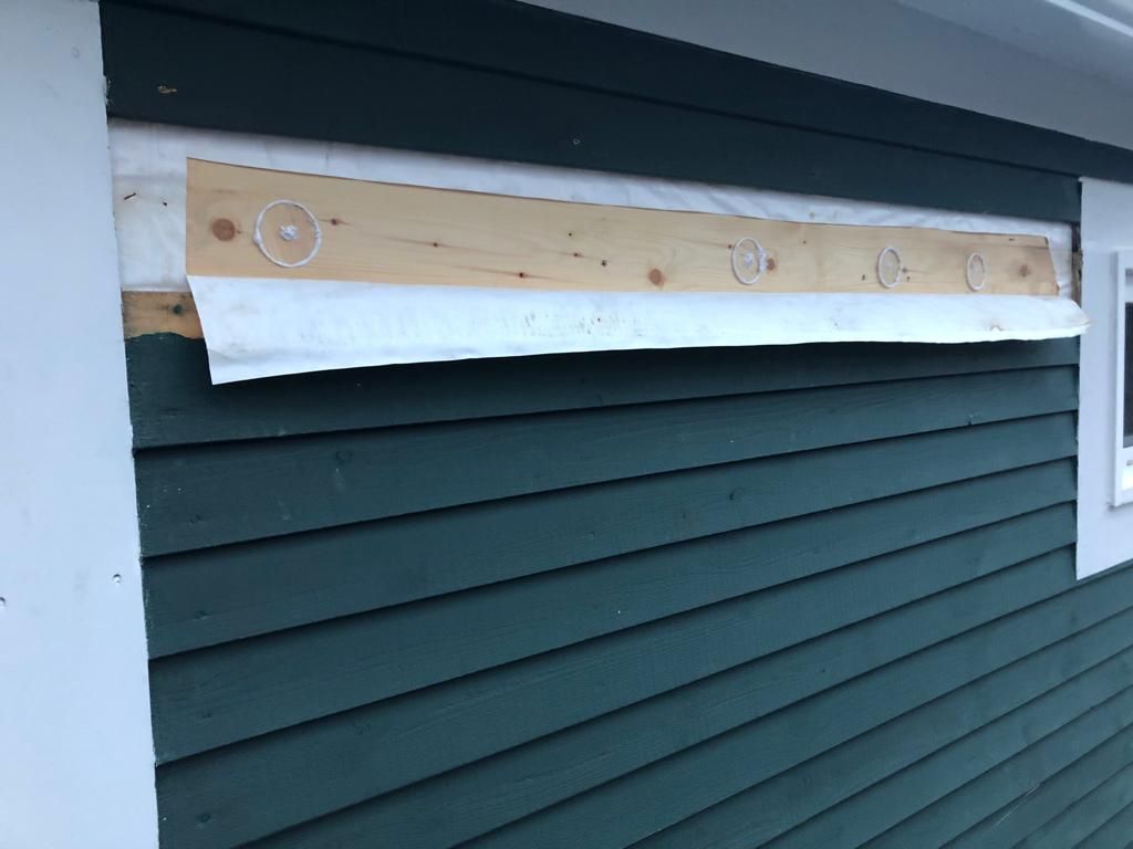 A green siding on a house with a window missing