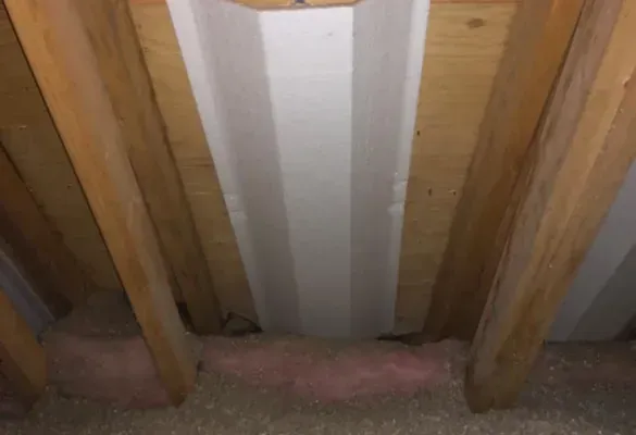 There is a white pipe in the ceiling of a room.