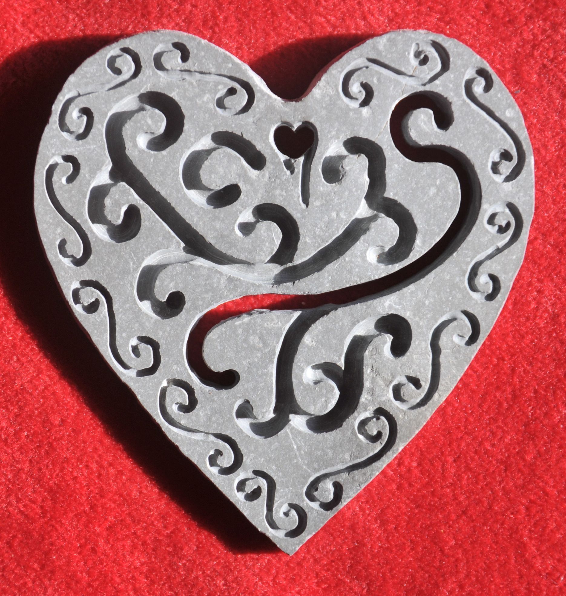 Hand cut and engraved stone pendant in shape of a heart