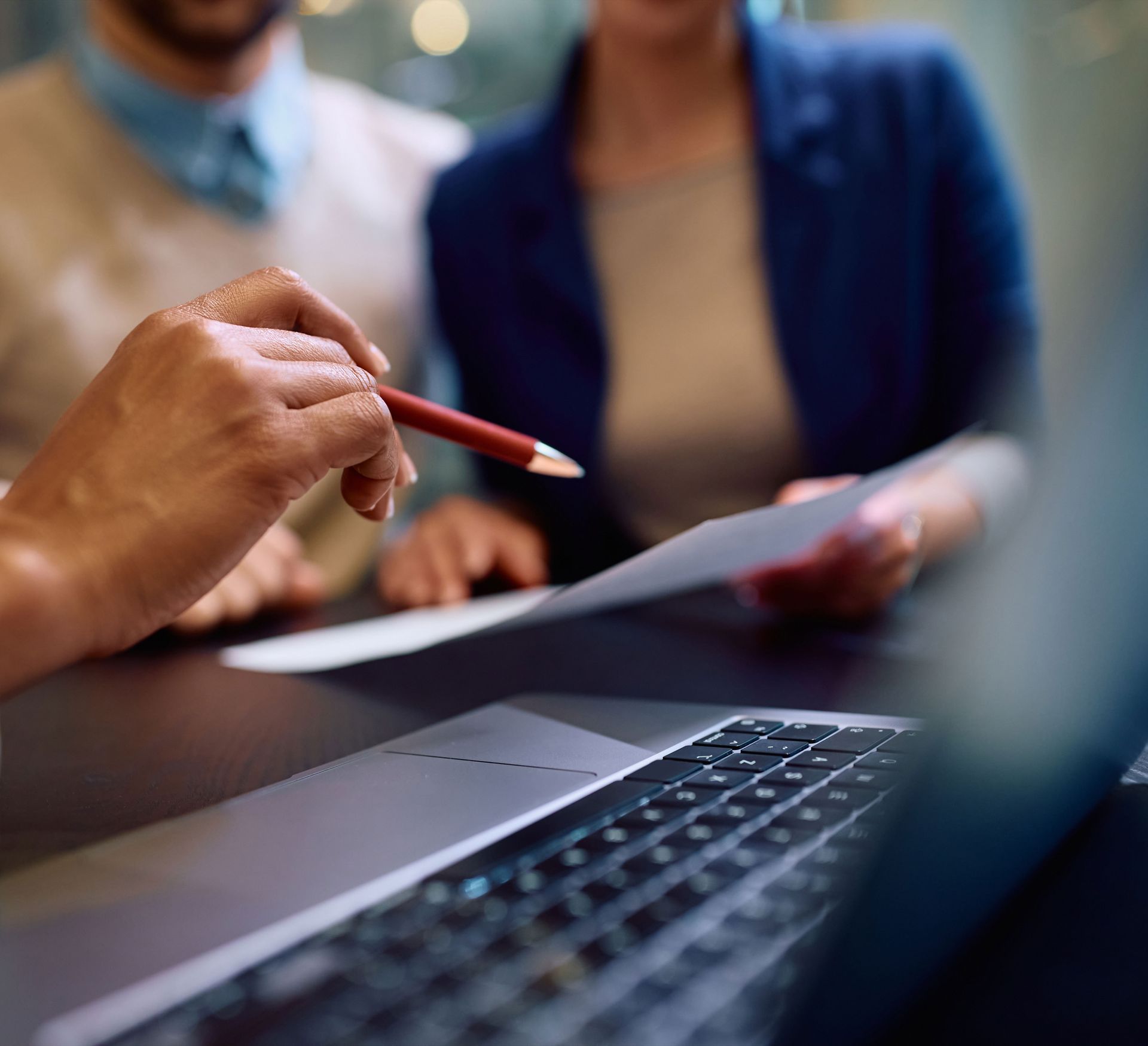 A person is holding a pencil in front of a laptop computer.