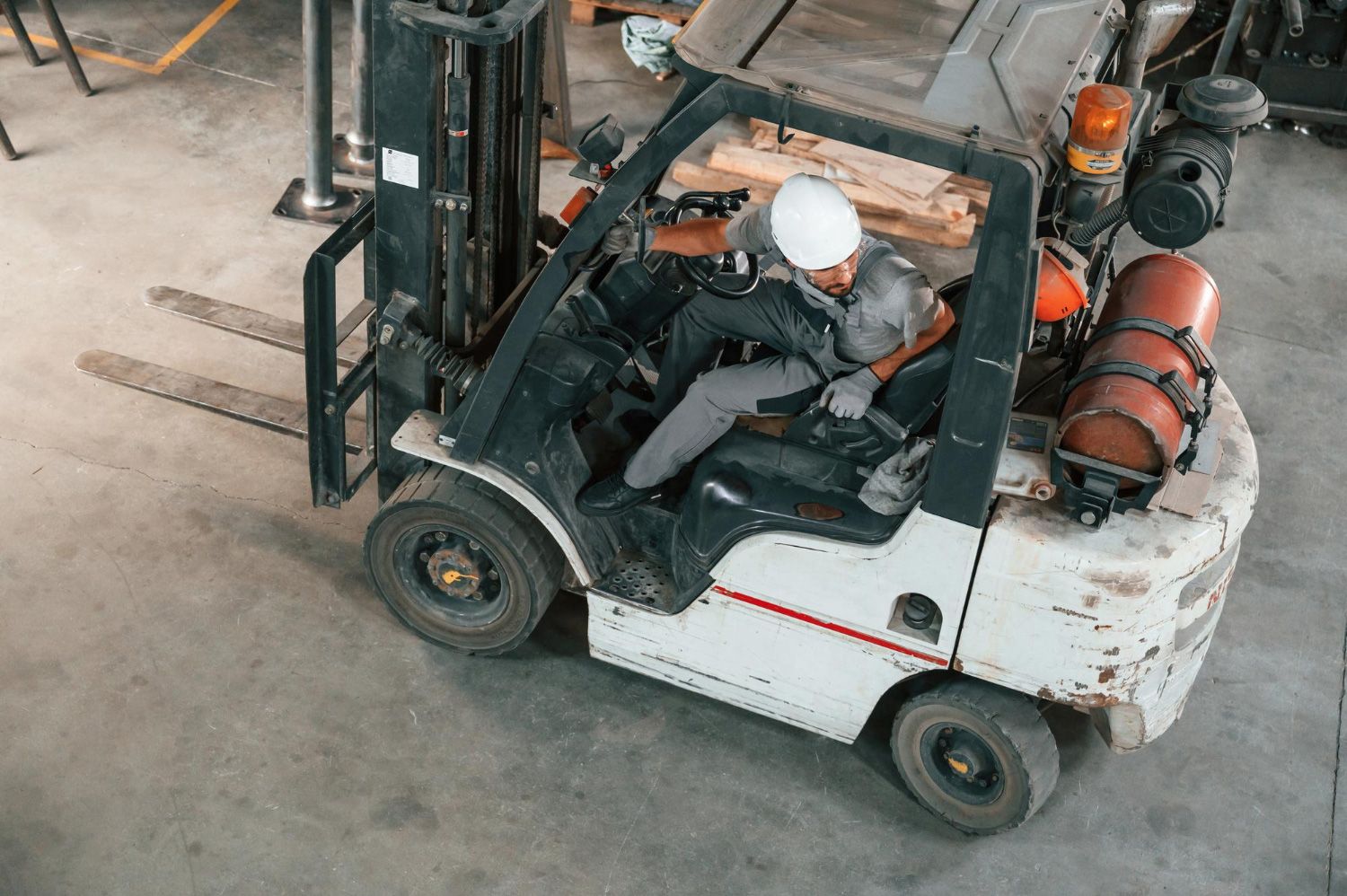 Worker driving a forklift in a warehouse, viewed from above.