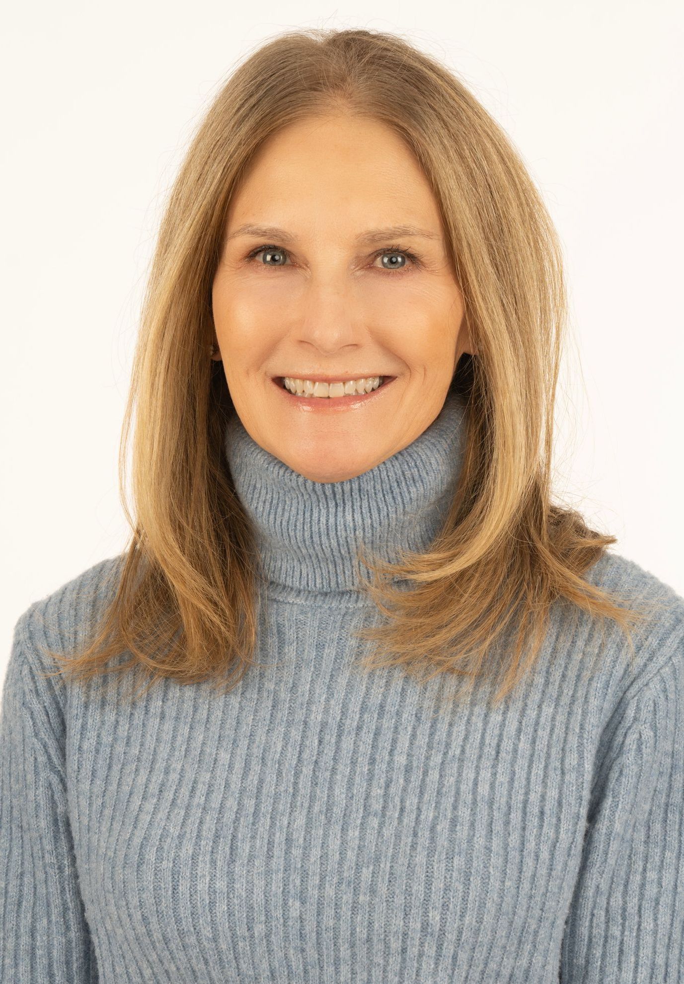 Smiling woman in a light blue turtleneck sweater against a white background