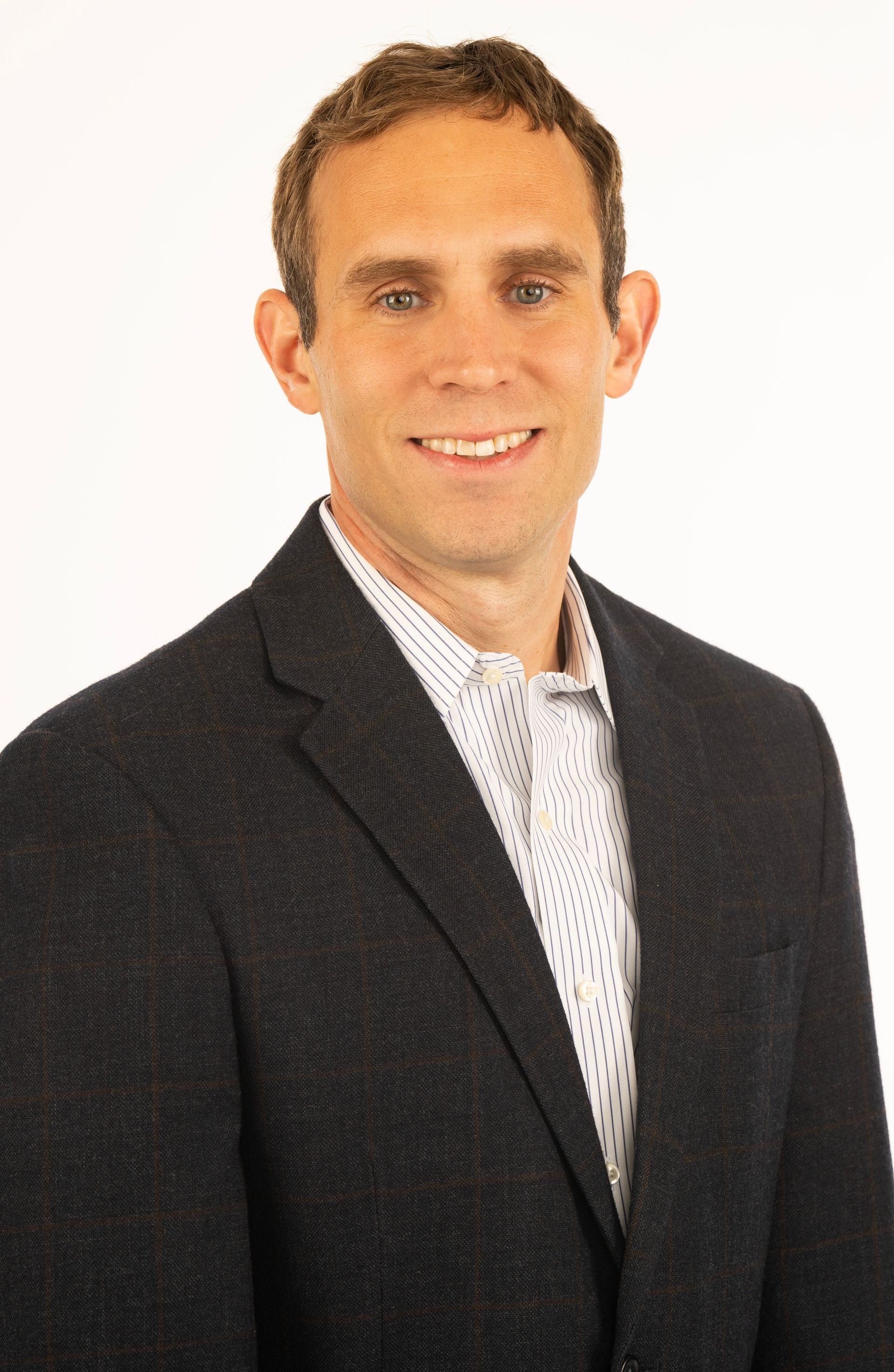 A man in a suit and tie is smiling for the camera.