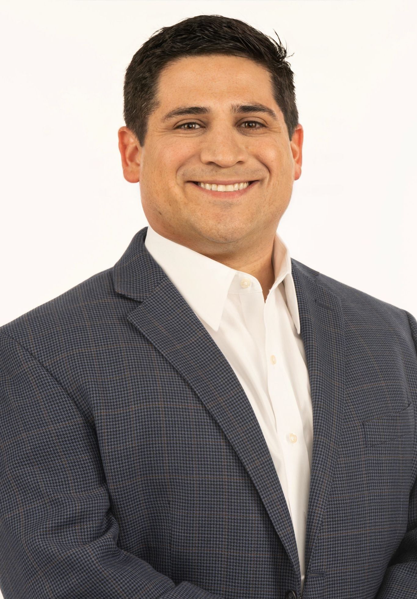 Attorney Will Ortiz in a suit and white shirt is smiling for the camera.