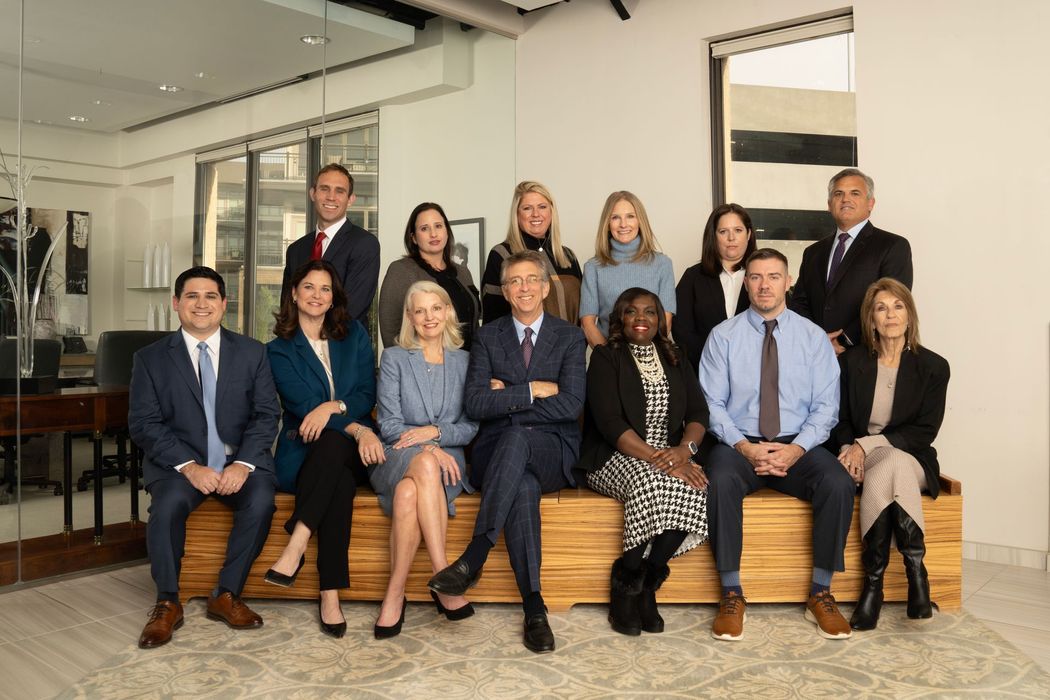 Group of people in business attire posing on steps in a bright office lobby