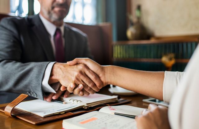 A close up of two people shaking hands in an office.