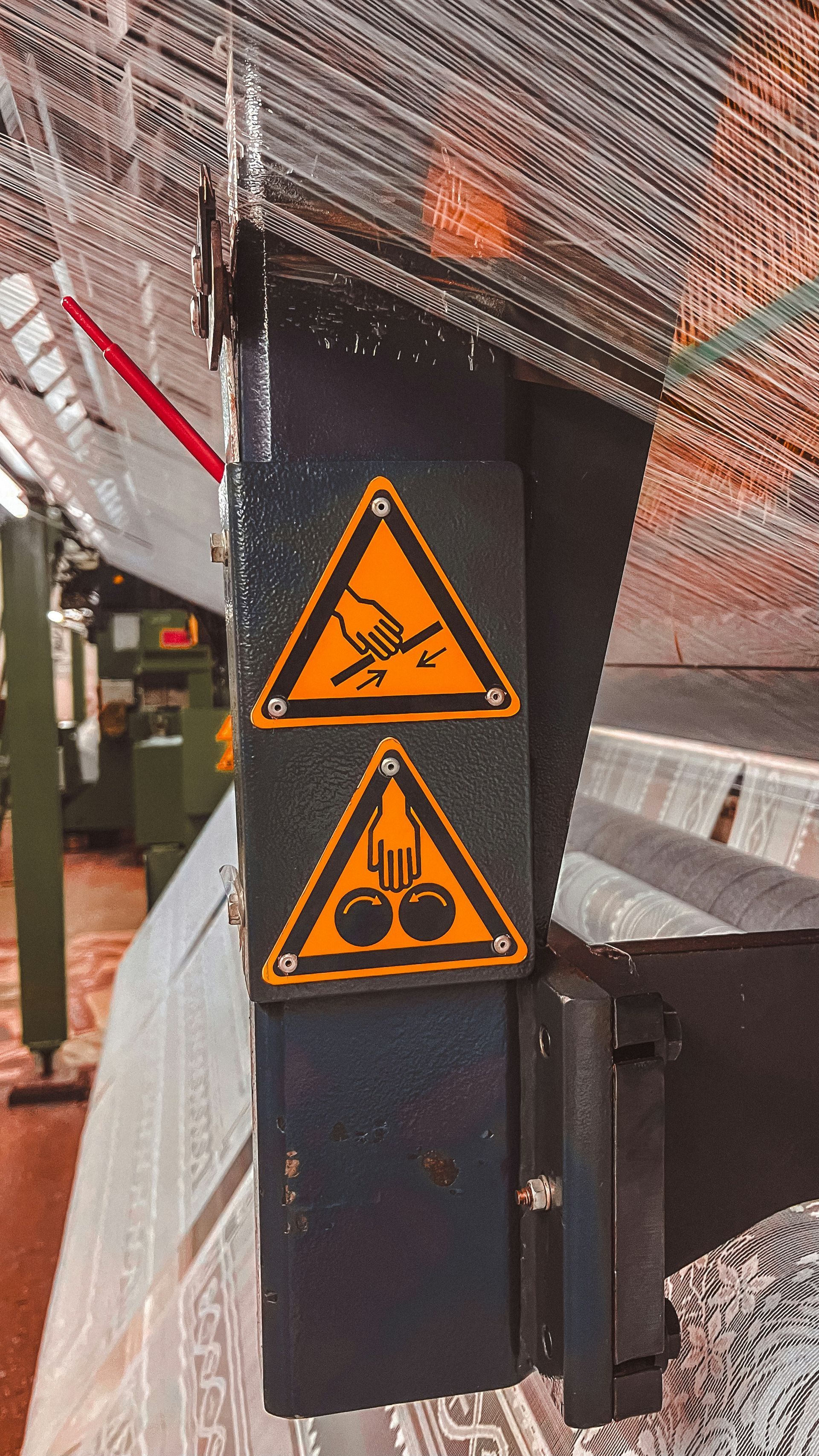 Orange warning signs on a black post beside a netted construction area