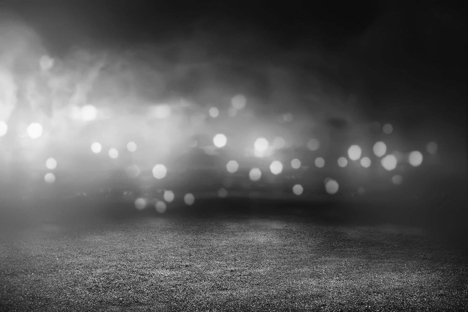 Black and white abstract with hazy lights and a textured ground.