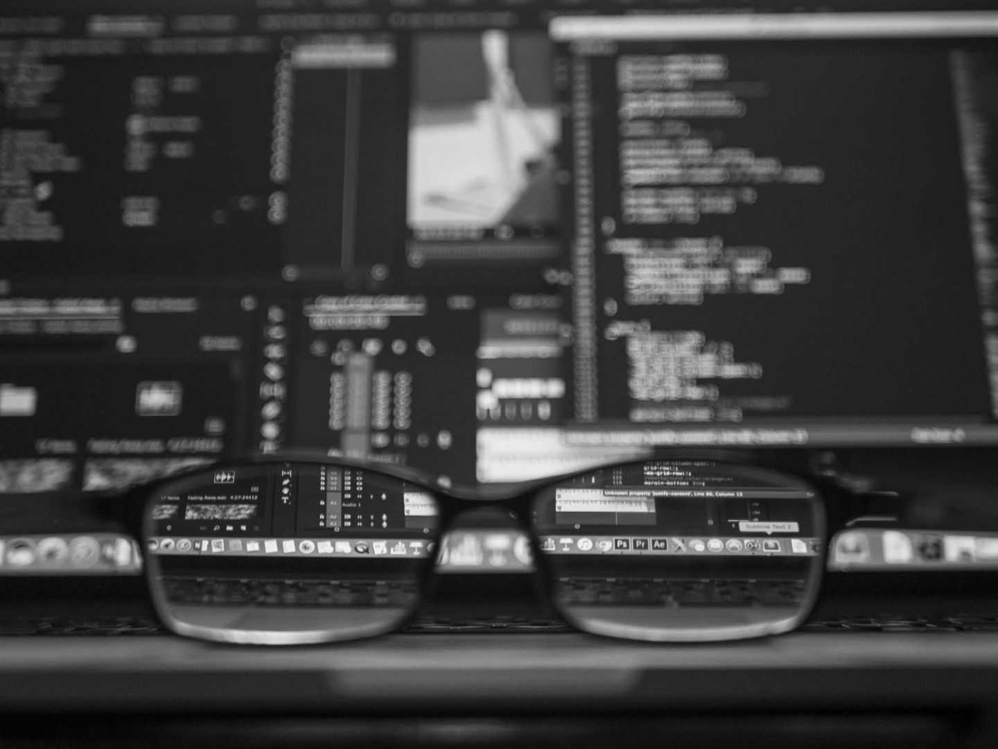 Glasses reflecting a computer screen displaying lines of code.