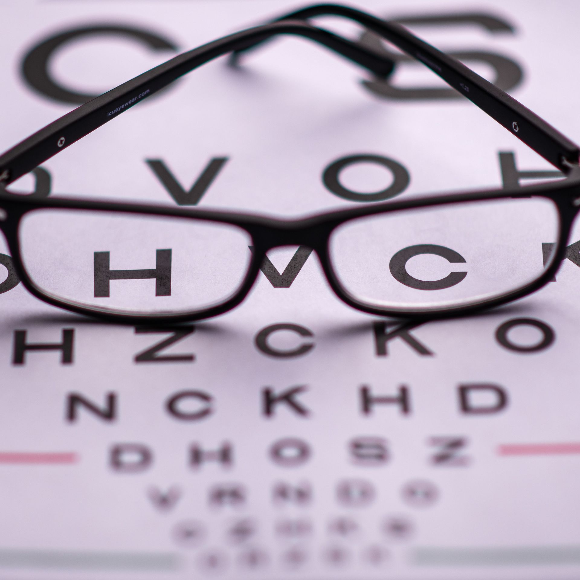 Eyeglasses on a vision chart, focusing on the letters HMC.