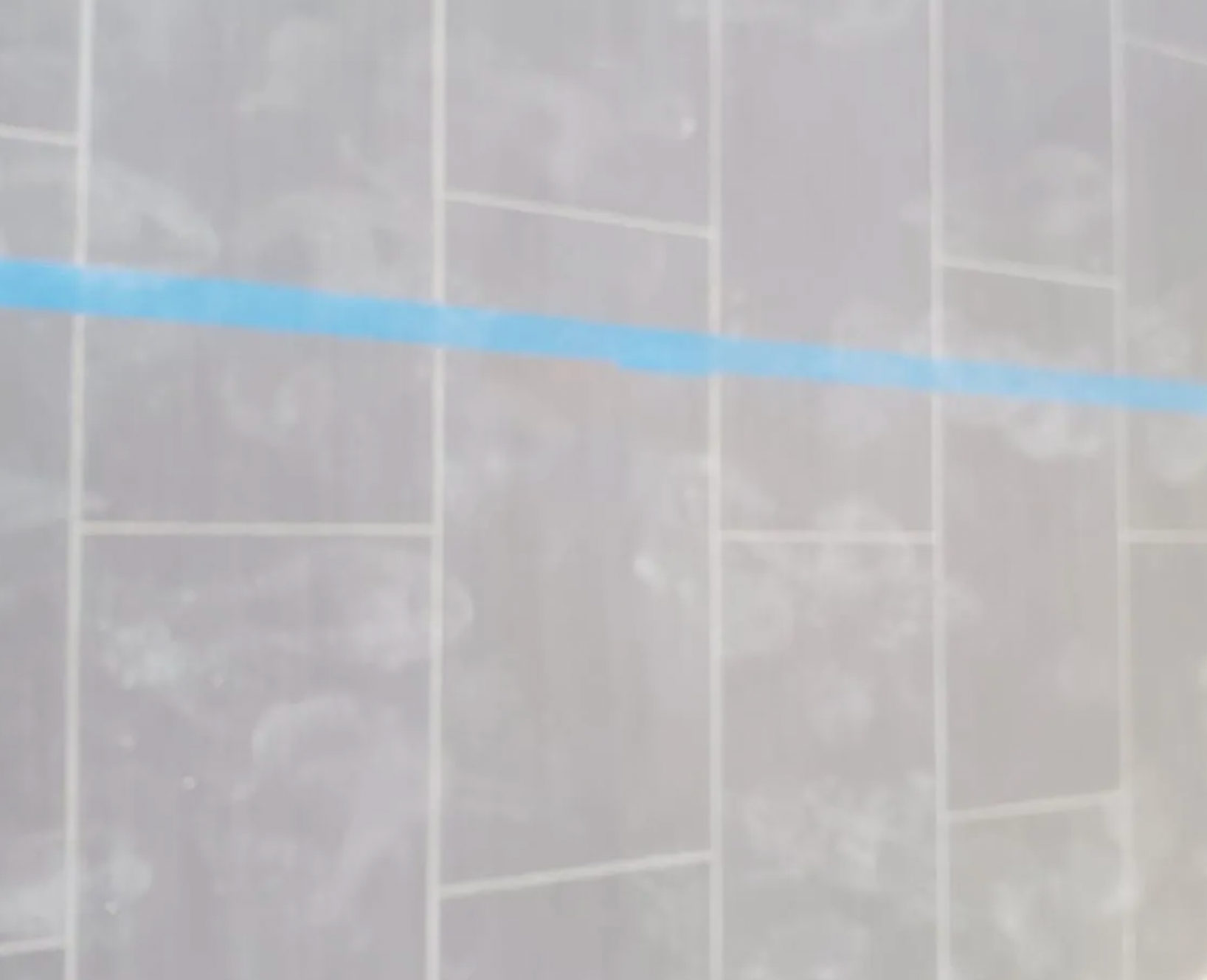 A close up of a tiled wall with a blue line on it.