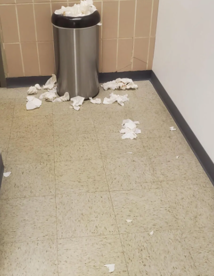 A trash can filled with tissues on the floor