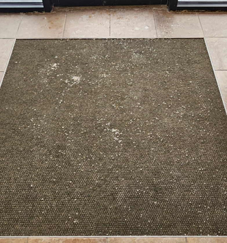 A dirty rug is sitting on a tiled floor