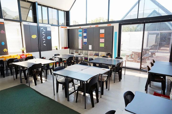 A classroom with tables and chairs and a large window