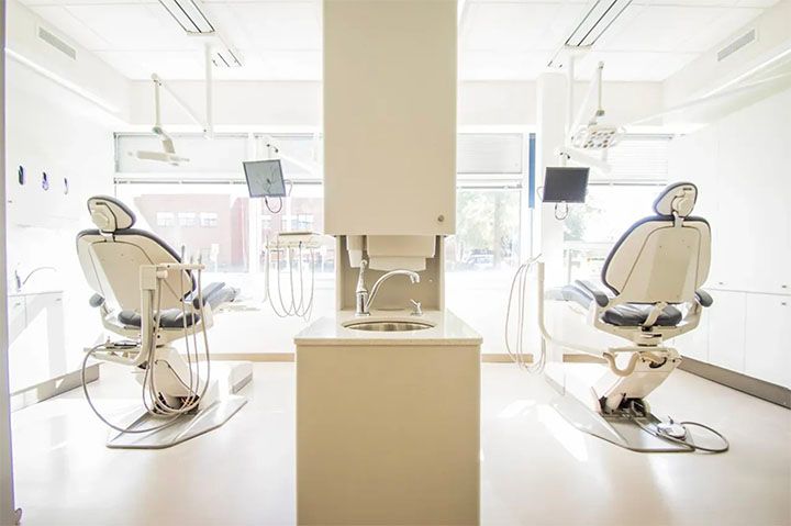 A dental office with two dental chairs and a sink.