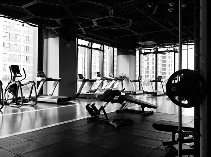 A black and white photo of an empty gym with treadmills and exercise bikes.