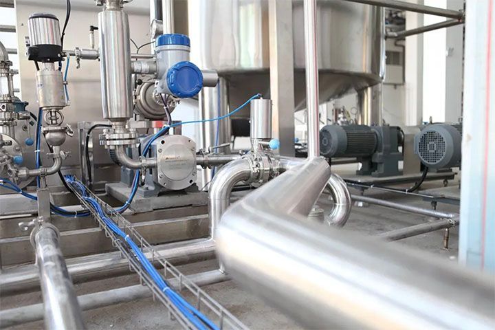 A factory with a lot of stainless steel pipes and pumps.