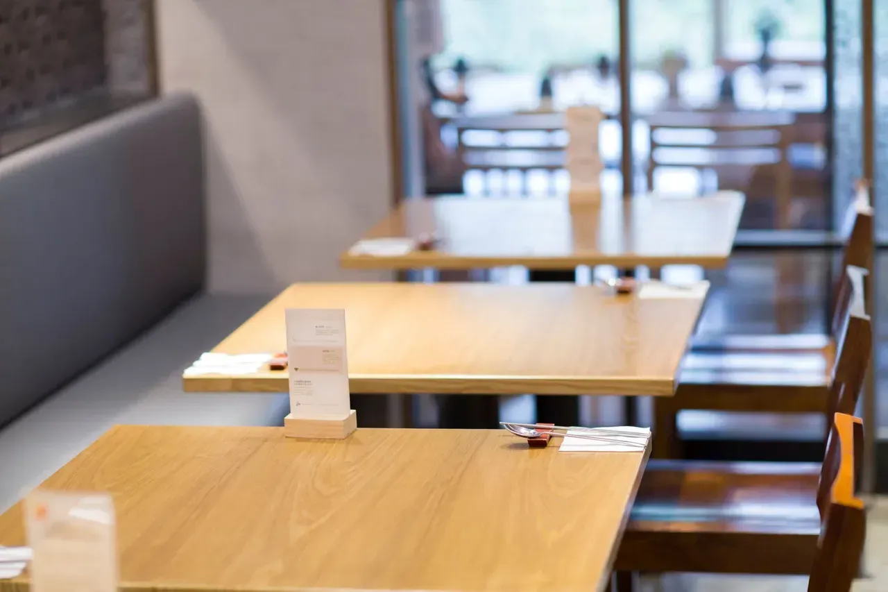 A row of wooden tables and chairs in a restaurant.