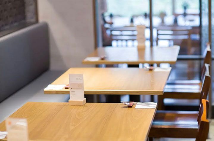 A row of wooden tables and chairs in a restaurant.