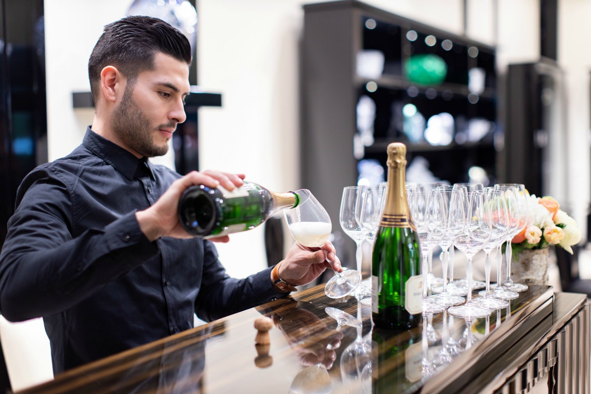 Male model bartender pouring champagne at a luxury pop up event at Crystals Aria Las Vegas.