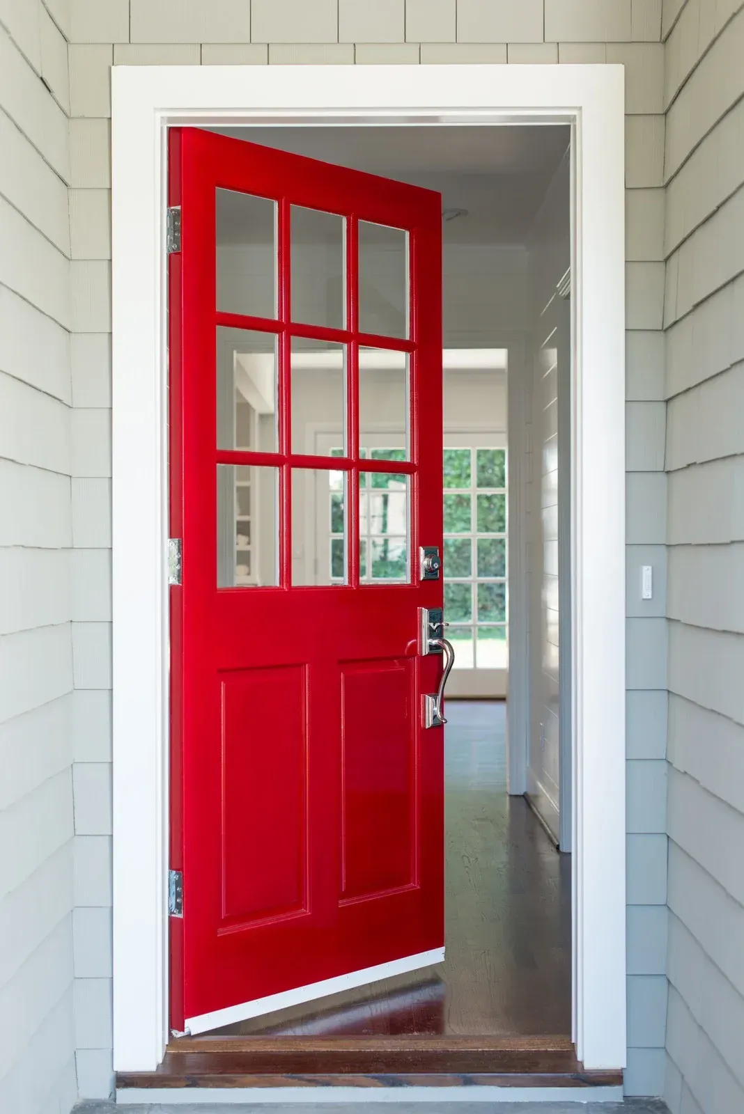 Red front door open, showing interior hallway and windows; white trim and siding.