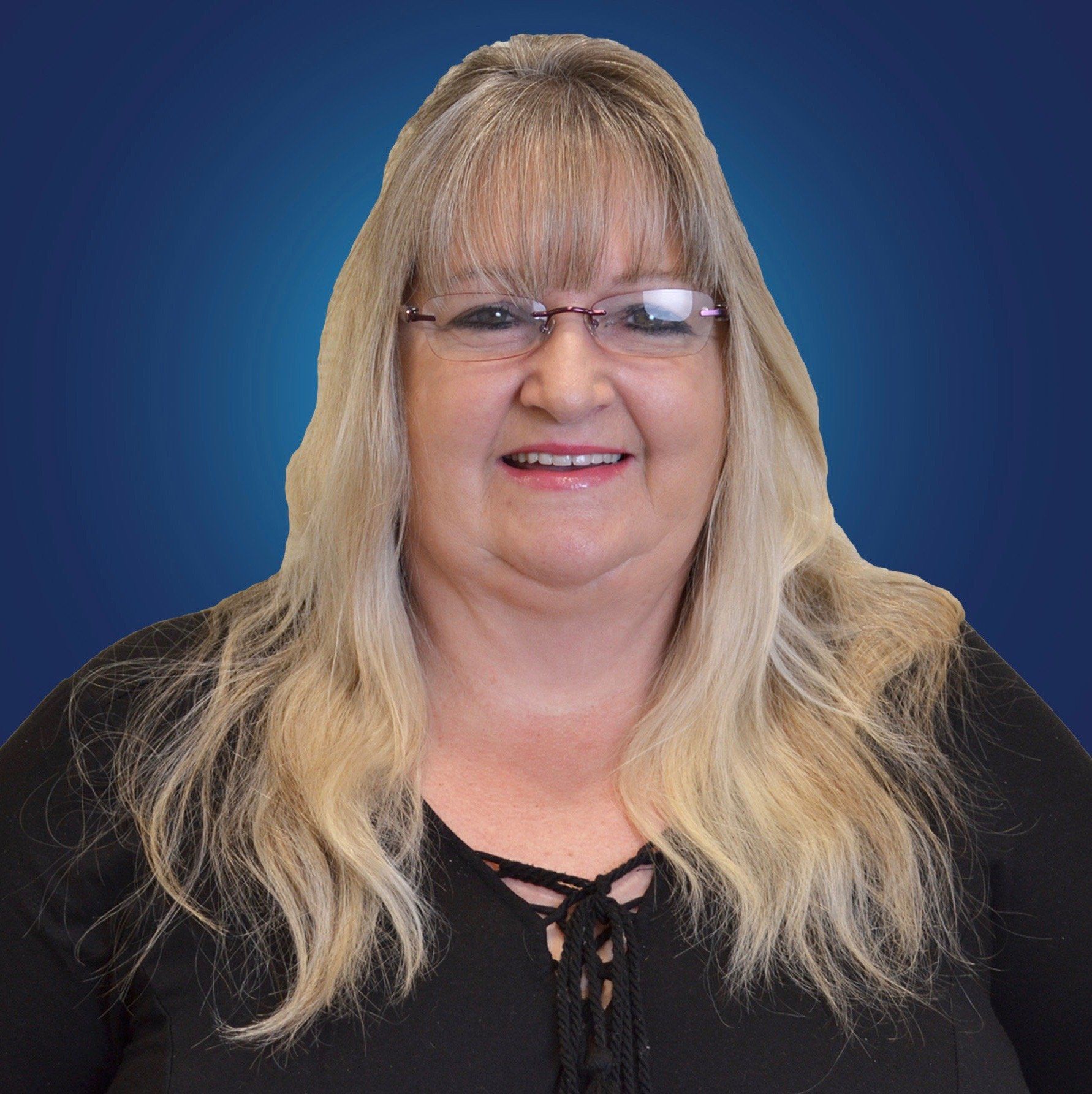 A woman wearing glasses and a black shirt is smiling for the camera.