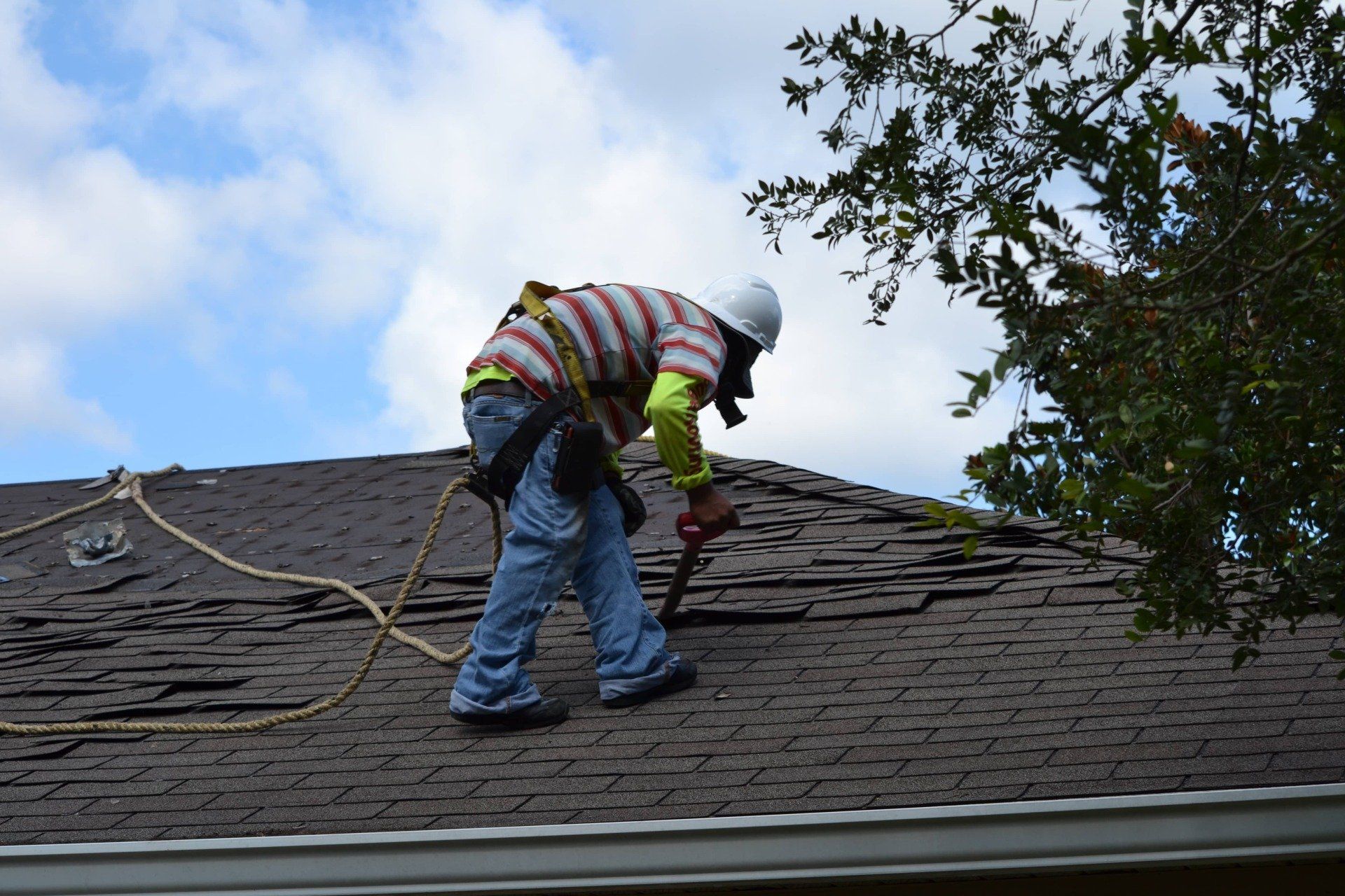 A man is working on a roof with a drill.